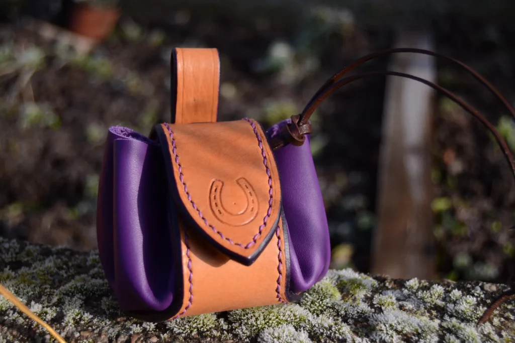 Bourse en cuir violet, renforcée par une bande en cuir. Fermeture pression.